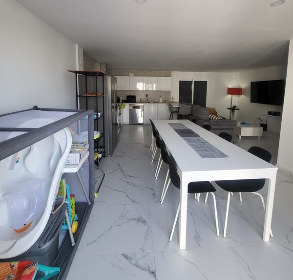 Long dining table next to the kitchen, with a children's playpen