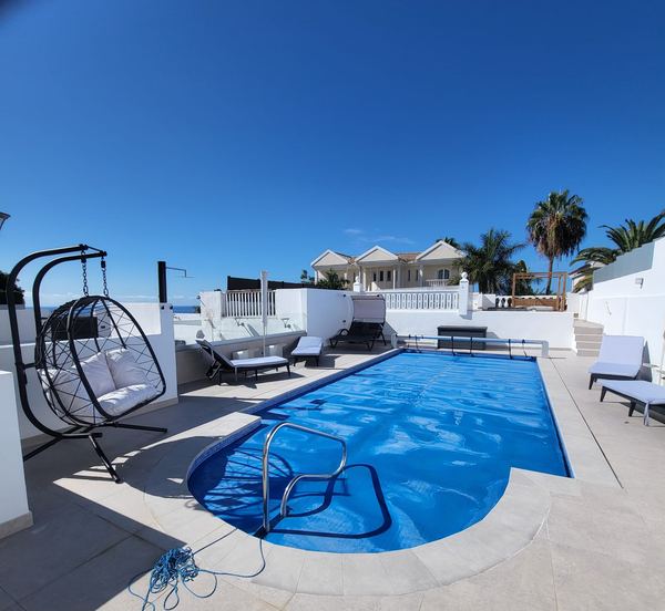 Private heated pool with solar cover, hanging egg chair, sun loungers and palm trees