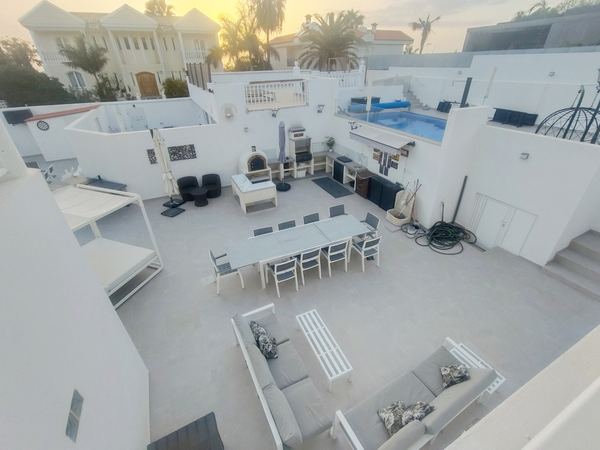 Aerial view of the terrace at sunset with outdoor lounge, large dining table, pizza oven and barbecue
