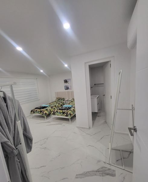 Twin bedroom with tropical-print bedding, air conditioning and en-suite door